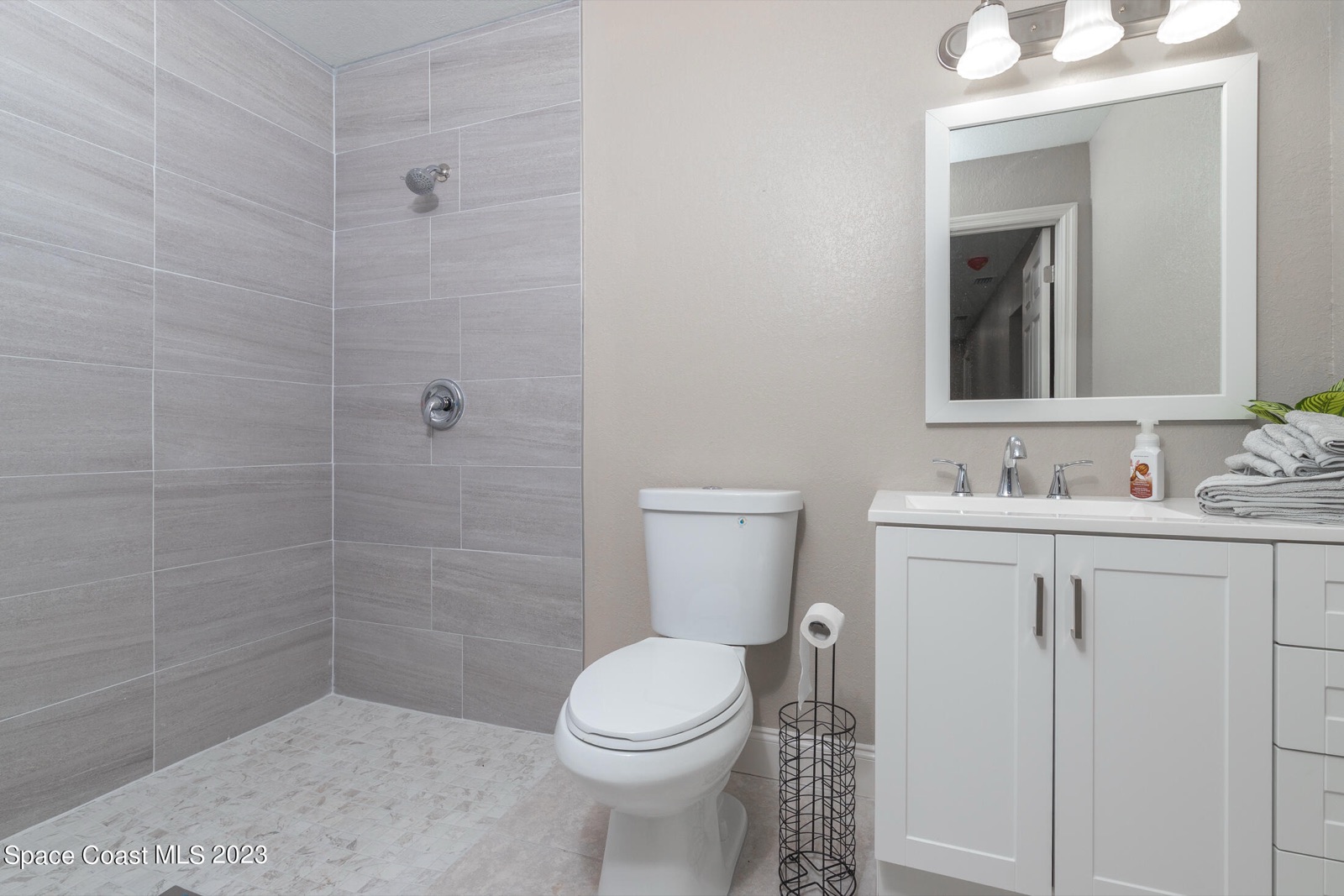 Master bathroom after — fresh gray tile, new vanity, modern fixtures