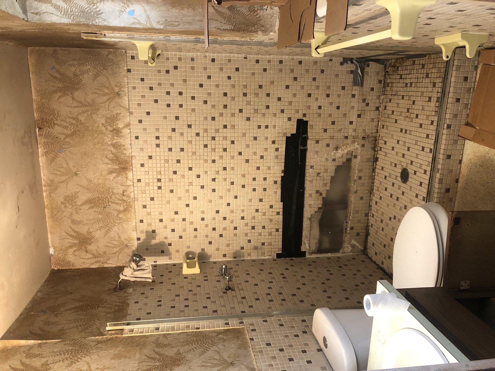 Master bathroom before — dated tile, worn fixtures, peeling paper